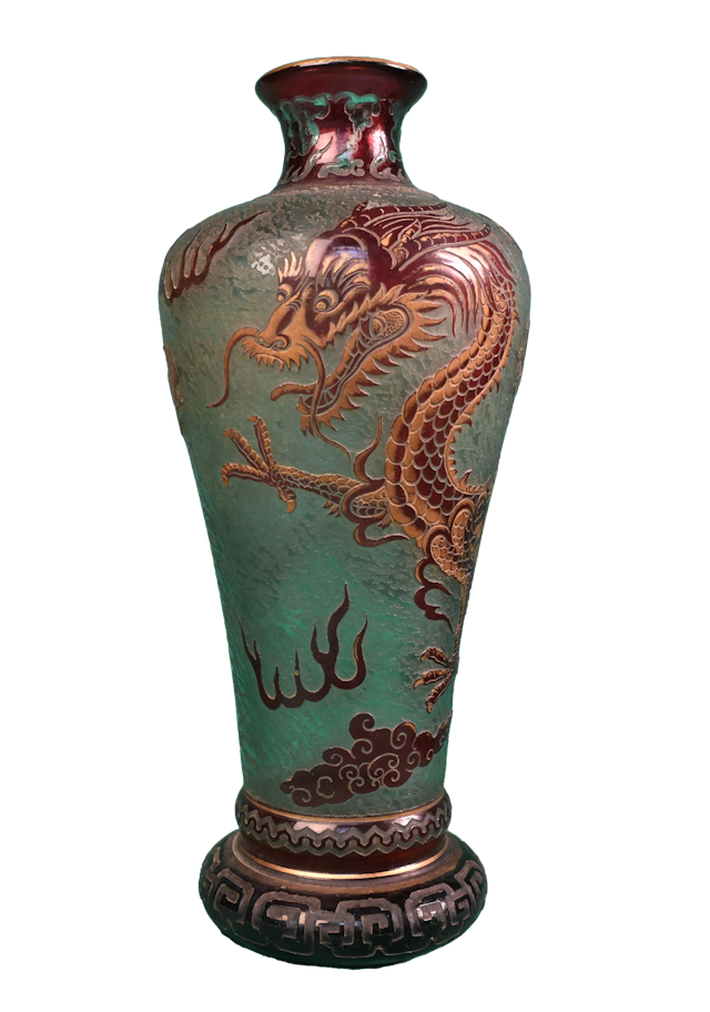 Ce vase au décor de dragon fut créé par la cristallerie Saint-Louis avant 1900.    La cristallerie Saint-Louis fut fondée en 1585 dans la vallée de Münzthal. Elle travailla d’abord le verre, avant de percer le secret de la fabrication du cristal en 1781.    Le corps du vase, en verre multicouche, présente un fond vert jade gravé à l’acide qui permet, grâce à l’alternance de zones brillantes et de zones plus mates, d’évoquer l’air dans lequel évolue le dragon.    La couche colorée supérieure, rouge, fait apparaître les motifs du dragon et des chauves-souris, ainsi que les nuages. Les lignes gravées laissent transparaître la teinte du fond du vase, tandis que certains détails sont rehaussés d’or, ce qui donne à la figure fantastique profondeur et vie.    L’inspiration chinoise de la pièce est particulièrement sensible dans les motifs qui ornent le vase. Le dragon est un motif éminemment extrême-oriental ; le traitement des nuages s’inscrit également dans un mode de représentation orientalisant ; enfin, les flammes sont représentées de la même manière dans l’art chinois que sur notre vase. Il est même probable qu’un modèle chinois existant ait été copié pour la réalisation de cette pièce.    Le musée Saint-Louis conserve dans ses collections un vase identique à celui-ci. 
