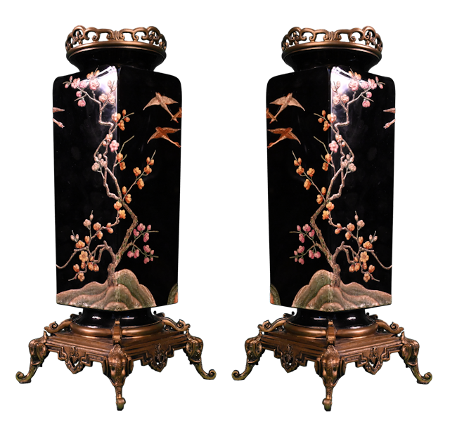 Cette paire de vases au décor japonisant fut réalisée par la cristallerie Baccarat vers 1880.   Elle créa ces vases de forme carrée en cristal noir reposant sur une monture de bronze.  Ces œuvres sont ornées d’un décor naturel d’une grande poésie exécuté grâce à la technique de l’émaillage à chaud en relief.   Fondée sous Louis XV, la manufacture de cristal française Baccarat fit montre de son excellence aux Expositions Universelles, tout au long du XIXe siècle.   La couleur noire du cristal hyalite est obtenue grâce à l’injection de scories ou de soufre dans le verre. Ce fond sombre met en valeur le décor peint.   Ici, il permet de créer un décor exécuté à l’imitation des plaques de laque chinoise ou japonaise : sur le fond noir se détachent des branches de cerisier en fleurs, autour desquelles volent des oies sauvages. Les dessins des deux vases se répondent selon une symétrie axiale.   Les couleurs vives se détachent nettement sur le fond, qui met en avant la minutie et le sens du détail mis en œuvre pour ce décor.   La monture en bronze, présente au sommet et à la base des vases, adopte également un style orientalisant : le vase repose sur quatre têtes d’éléphant appuyées sur leur trompe.   Un dessin préparatoire conservé dans les archives de la cristallerie montre un vase dont le décor japonisant fut conçu selon le même principe d’imitation de la laque par le cristal noir. 
