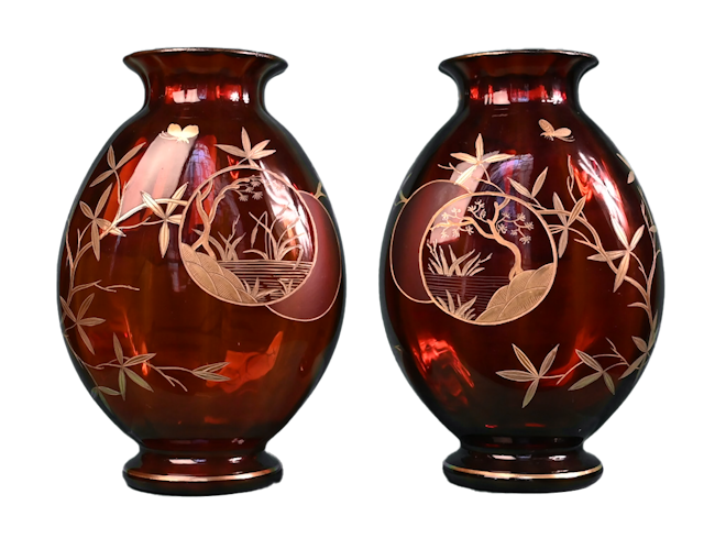 Cristallerie Saint-Louis, Paire de vases rubis au décor japonisants, v. 1880    Cette paire de vases aux cigognes fut exécutée par la cristallerie Saint-Louis vers 1880.    La cristallerie Saint-Louis fut fondée en 1585 dans la vallée de Münzthal. Elle travailla d’abord le verre, avant de percer le secret de la fabrication du cristal en 1781.    Ces vases en cristal rubis sont ornés de motifs japonisants. Ceux-ci furent gravés à l’acide, puis émaillés d’or.    A côté de la cigogne, un arbre d’essence extrême-orientale s’épanouit sur la panse.    Il est accompagné d’un papillon.    A l’opposé de la cigogne se trouvent deux cartouches circulaires emboîtés, présentant de légères variations d’un vase à l’autre.    Le premier cercle accueille un paysage japonisant (une étendue d’eau bordée de roseaux, un arbre évoquant un pin sur un rocher).   Le second est dépoli, ce qui donne à la couleur rouge un aspect mat.    Les vases sont signés à l’or : « St Louis » et portent une étiquette ancienne de la cristallerie.    Une paire de vases du même modèle sont conservés en collection particulière. 